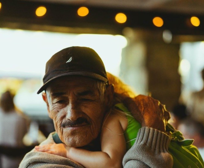 An older man holding a young child on his shoulders